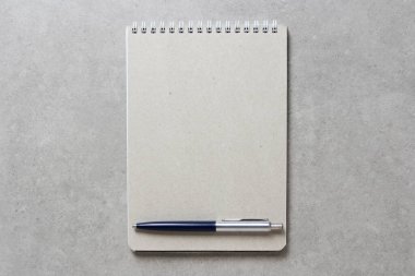 Açık gri beton arkaplanlı tükenmez kalemle kaplı bir el işi kâğıdı olan bir yay defteri. Yeni fikir, iş planı ve strateji kavramı, içeriğin geliştirilmesi ve uygulanması. Metin için boş boşluk.