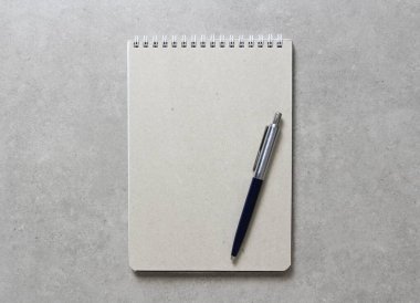 Açık gri beton arkaplanlı tükenmez kalemle kaplı bir el işi kâğıdı olan bir yay defteri. Yeni fikir, iş planı ve strateji kavramı, içeriğin geliştirilmesi ve uygulanması. Metin için boş boşluk.