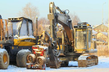 11.21.2020 Syktyvkar, Rusya, açık ve soğuk bir günde kırsal bir kış manzarasının arka planına karşı ormancılık makineleri hasat ve forvet. Boş metin ve tasarım alanı olan stok fotoğrafı