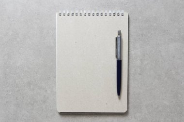 Açık gri beton arkaplanlı tükenmez kalemle kaplı bir el işi kâğıdı olan bir yay defteri. Yeni fikir, iş planı ve strateji kavramı, içeriğin geliştirilmesi ve uygulanması. Metin için boş boşluk.