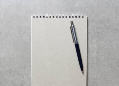 Açık gri beton arkaplanlı tükenmez kalemle kaplı bir el işi kâğıdı olan bir yay defteri. Yeni fikir, iş planı ve strateji kavramı, içeriğin geliştirilmesi ve uygulanması. Metin için boş boşluk.