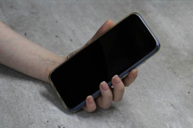 Açık gri arka planda siyah ekranlı, beyaz bir kadın el. İş ve modern teknolojiler kavramı, çevrimiçi iletişim fotoğrafı metin ve tasarım için boş alan.