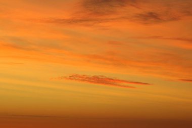 Ufkun altında güneş ve gün batımında veya şafakta güneşin aydınlattığı ateşli turuncu gökyüzünde bulutlar. Metin ve tasarım için yer.