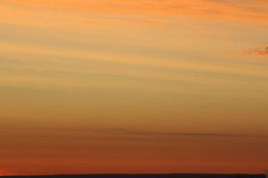 Ufkun altında güneş ve gün batımında veya şafakta güneşin aydınlattığı ateşli turuncu gökyüzünde bulutlar. Metin ve tasarım için yer.
