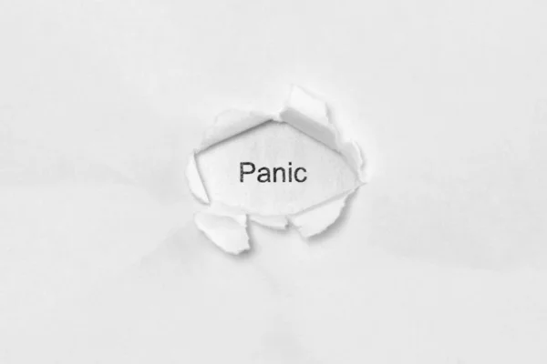 Parola panico su sfondo bianco isolato attraverso il foro della ferita nella carta. — Foto Stock