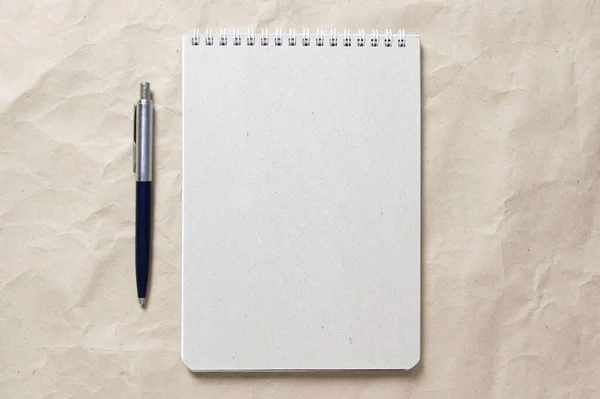 白いコイル状の春とベージュの背景にペンでグレーのメモ帳クラッシュクラフト紙 — ストック写真
