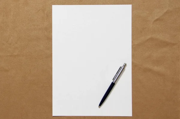 Modèle de papier blanc avec stylo repose sur un fond en tissu brun clair. Concept de plan d'affaires et de stratégie. Photo de stock avec espace vide pour le texte et le design — Photo