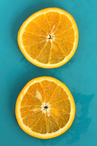 Primer plano de dos rodajas redondas de cítricos naranjas sobre fondo azul, humor fresco de verano — Foto de Stock