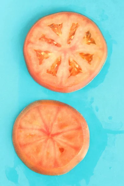 파란 배경에 둥근 붉은 토마토 두 조각을 덮으면 신선 한 여름 기분 이 난다. — 스톡 사진
