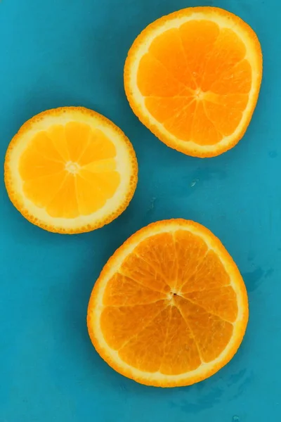Primer plano de tres rodajas redondas de cítricos naranjas sobre fondo azul, humor fresco de verano — Foto de Stock