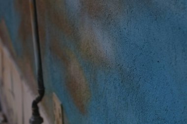 Kalıplı mavi bir duvar renkli bir şehir duvar resmi detayına sahiptir, canlı bir şehirde bulunan sanatsal ifadeyi vurgular. Sahne şehir kültürünü yansıtıyor.