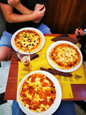 Palmiye ağaçları ve çizgili tentelerin bulunduğu canlı bir kafe, ziyaretçileri hareketli bir alışveriş meydanında ağırlayarak bulutlu gökyüzüne rağmen rahat bir atmosfer yaratıyor..