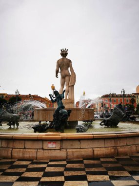 Palmiye ağaçları ve çizgili tentelerin bulunduğu canlı bir kafe, ziyaretçileri hareketli bir alışveriş meydanında ağırlayarak bulutlu gökyüzüne rağmen rahat bir atmosfer yaratıyor..