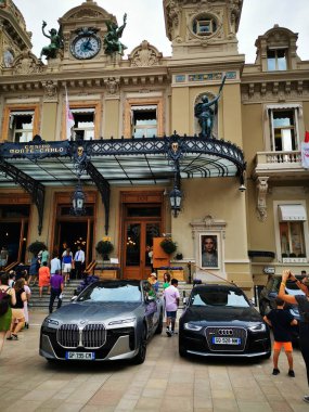 Büyük Monte Carlo Kumarhanesi 'nin önünde lüks BMW ve Audi araçları gururla dururken, turistler güneşli bir günde Monako' nun canlı atmosferinin tadını çıkarıyorlar..