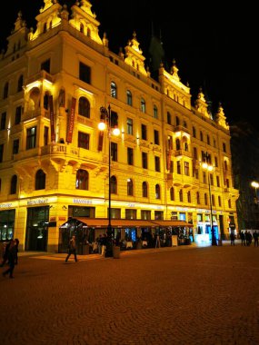 Çok güzel aydınlatılmış tarihi bir bina geceleri görkemli bir şekilde duruyor. Etrafı yayalarla çevrili kaldırım taşlarıyla çevrili. Canlı atmosferin keyfini çıkarıyorlar..