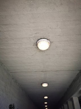 Dar bir yaya geçidinin tavanına bir dizi dairesel ışık monte edilir. Gün boyunca beton çevreye ışık saçar..