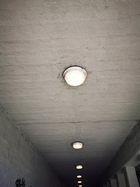 Dar bir yaya geçidinin tavanına bir dizi dairesel ışık monte edilir. Gün boyunca beton çevreye ışık saçar..