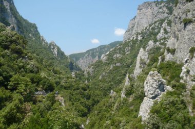 Sersemletici bir kanyon yükselen kayalık uçurumlar arasında uzanır, yemyeşil vadiyi sarar, ve parlak mavi gökyüzü bu sakin yaz manzarasını güçlendirir..