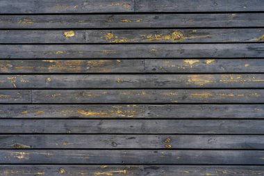 Eski ahşap duvarlardan yapılmış, siyah kabuklu boyayla boyanmış bir duvar.