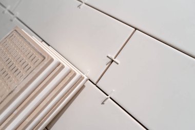 Duvarda taklit tuğlalar olan beyaz seramik fayanslar sergiliyor.