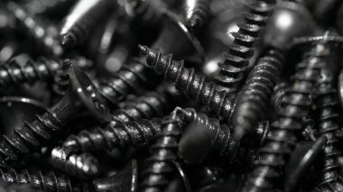 İnşaatın unsurları ve detayları. Bir sürü siyah vida. Yukarıdan bak. Doku. Geçmişi. İnşaat malzemeleri satışı. Bir grup kendini beceren vida etrafa saçılmış. Seçici odak