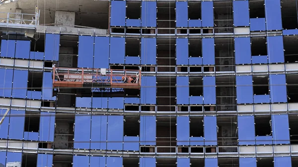 Çok katlı bir binaya cam bir cephe kurulumu. Binaların yapımı ve bakımı