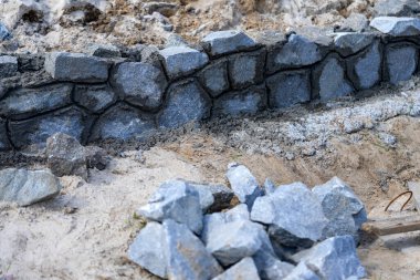 Doğal taştan yapılar ve binalar inşa ediliyor. Doğal granit çit yapım aşamasında.