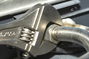 Tesisatçı boru tesisatını ingiliz anahtarıyla düzüyor. İletişim onarımı