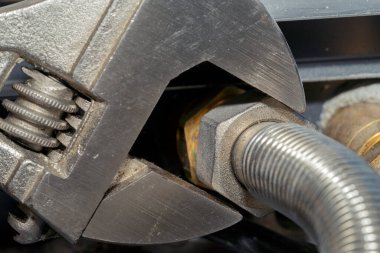 Tesisatçı boru tesisatını ingiliz anahtarıyla düzüyor. İletişim onarımı