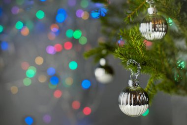 Yılbaşı selebrasyon kartı. Gümüş toplar ve renkli bokeh ışıklarıyla süslenmiş Noel ağacı.