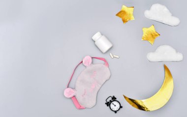 sağlıklı uyku konsepti. Tıbbi kapsüller ve gri arka planda çalar saat. Melatonin ve cyrcadian ritmi. Uyku haplarıyla damgalanmamış bir şişe. Ay ve yıldızların arka planı. uyku maskesi. 