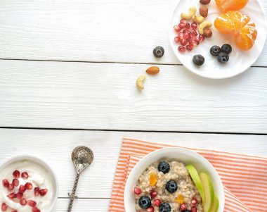 Kahvaltı, yabanmersini portakallı yulaf ezmesi ve sabah beyaz kasede fındık. Portakal ve nar tohumlu yulaf lapası. sağlıklı kahvaltı.