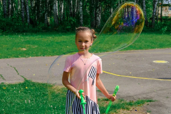 Chica jugando con gigante jabón burbujas al aire libre. — Foto de Stock