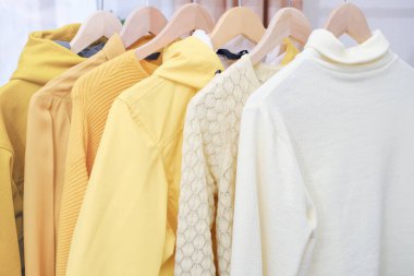 Askıda sarı renkli kadın kıyafetleri var. Bahar temizliği gardırobu. Minimum moda konsepti. 2021 'in modaya uygun rengi. Toplam sarı görünüm eğilimi. Tek renkli kıyafet..