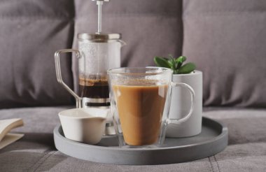 Kanepede beton tepside sütlü bir sabah kahvesi. özen ve aşk kavramı. Sıcak sabah estetik atmosferi için cam pres ve sulu bir çiçek. en küçük biçim.