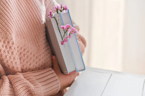 a girl with books and pink flowers, crop view. spring coming concept. blogger content, reading and back to school.