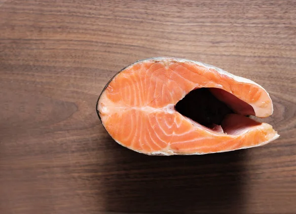 fresh raw salmon steak on wooden kitchen cutting board. fish menu as omega-3 and fatty acids source. cross section of salmon, top view.