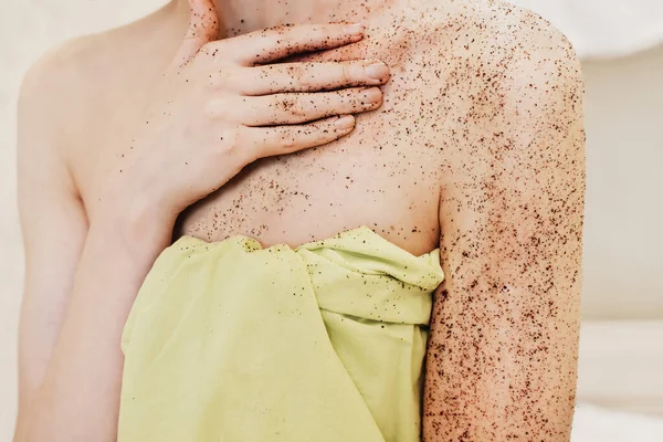 woman applying body exfoliating scrub. natural organic coffee polish on a woman\'s hands and breast. crop view. home spa concept.