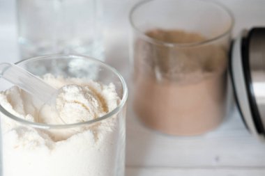 Protein tozuyla kavanozlardaki beyaz proteinin görüntüsünü kapat. Çikolata ve vanilya aromalı. Sağlıklı eklemler için ve güzellikle yüzleşmek için..