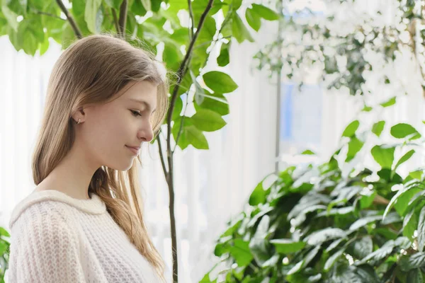 Side portrait of a teenager girl in a modern house with lots of green plants on a background. generation z concept — Stock Photo, Image