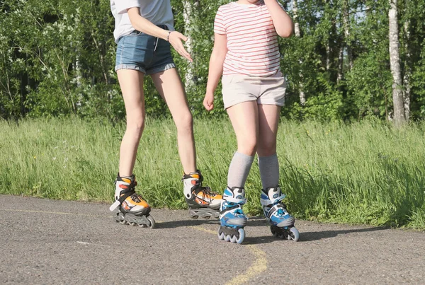 Teenager girl and her little sister rollerskating in the park. partial view. sport and leisure concept. preshcool girl and teen spending time together — Stock Photo, Image