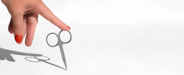 female hand touching nail scissors. manicure concept. nail care, beauty tools. banner size