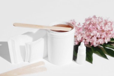 Tüy dökücü balmumu beyaz kapta spatula ve saç bantlarıyla temizleniyor. Cilt bakımı, pürüzsüz cilt tedavisi. ev tüy dökümü seti. 