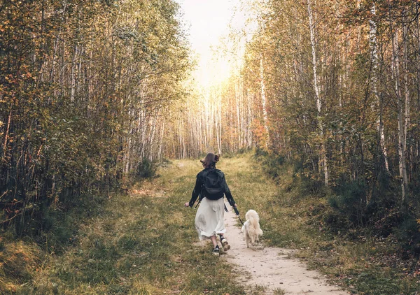 Back view of young woman running with her dog along a path in the forest. walking with pets, togetherness concept. — Stock Photo, Image
