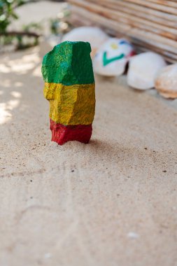 Gana 'nın renkleriyle boyanmış kumlu bir sahilde bir taş doğanın güzel bir süsü olarak yeşil, sarı ve kırmızıya boyanmış.