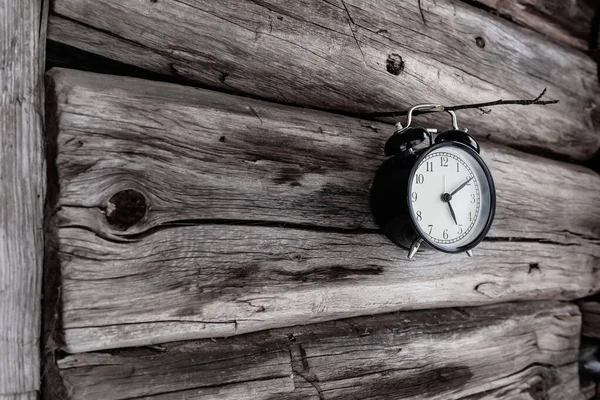 A bell hanging on a thin wooden stick stuck in an old log house