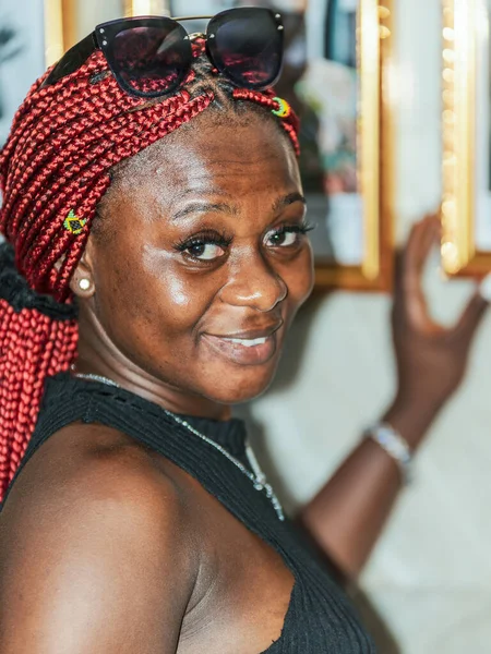 アフリカ人女性が笑顔でアクラ ガーナの壁に吊るされたものを見せる — ストック写真