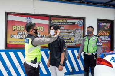 KARANGanyar, INDONEZYA - 10 Kasım 2020: Endonezya trafik polisi COVID-19 önleme sağlık protokolü üzerinde disiplin operasyonları yürütür. Dağıtım ve insanlara maske takmak.