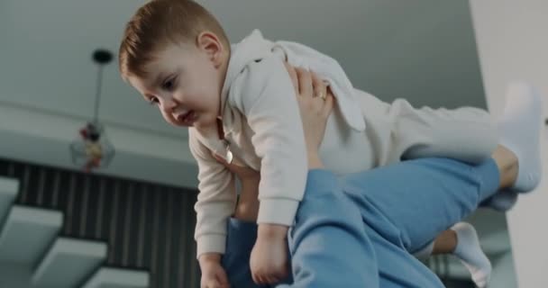 La madre está jugando con el niño pequeño en casa acostado en la cama. Niño feliz. — Vídeo de stock