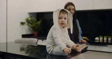 Bir çocuk masaya oturur ve kurabiye yer.